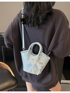 Fashionable light blue handbag with pearl bow and lace trim shown as a crossbody bag