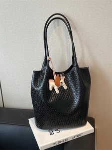 Minimalist black woven tote bag with a white Pegasus charm on a decorative pedestal