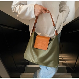 Détail du sac cabas en nylon vert armée avec bandoulière en cuir marron et logo embossé