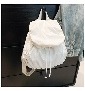 Detail of white pleated nylon backpack featuring drawstring closure and textured fabric