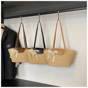 Detail of hand-woven straw tote bags with leather flaps and elegant pearl heart charms