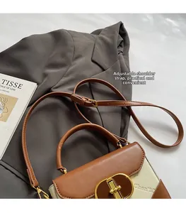 Detail view of contrast vintage handbag with gold oval lock and adjustable shoulder strap