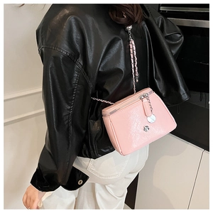 Détail du sac à bandoulière rose en cuir PU matelassé avec logo camélia et bandoulière chaîne