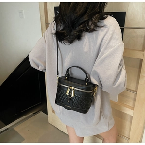 Close-up of black woven PU bucket bag with gold hardware and FASHION tag decoration