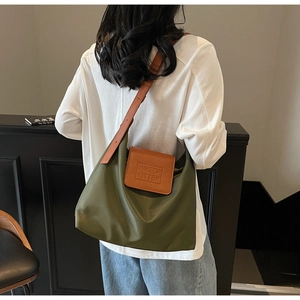 Détail du logo MAKEUP KITTEN embossé sur un sac cabas vert en nylon avec sangle en cuir brun