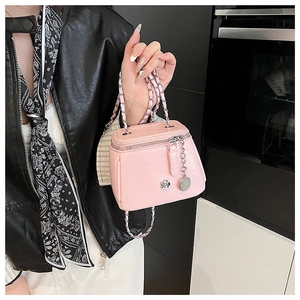 Détail d'un sac à main rose en cuir avec anse en chaîne argentée et pendentif fleur
