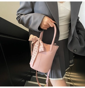 Close-up of pink bucket bag with lychee texture leather and decorative silk scarf bow