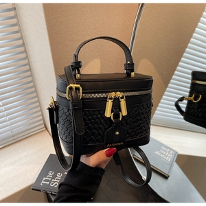 Detail of a black leather woven handbag with gold hardware and mirrored reflection