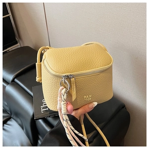 Dettaglio della mini borsa a tracolla gialla con trama litchi, logo PAN TOR e ciondoli