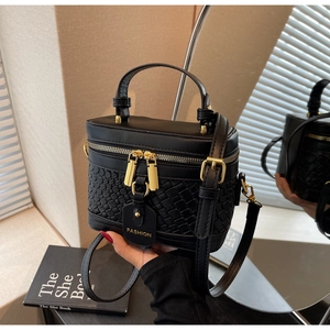 Detail view of black textured bucket bag with gold hardware and mirrored reflection