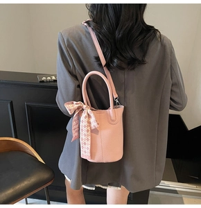 Pink pebbled leather bucket bag detailed with decorative scarf and adjustable shoulder strap