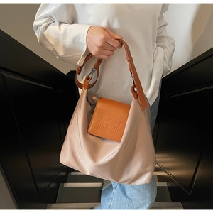 Détail du satin champagne brillant et du rabat en cuir orange avec gaufrage de texte