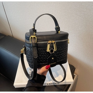 Detail of black PU leather bucket bag with woven texture and gold dual zipper hardware