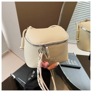 Dettaglio borsa a tracolla crema con texture litchi, zip argento e ciondolo a cuore