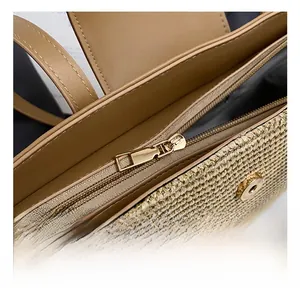 Close-up of woven straw beach bag featuring brown leather trim and golden metal zipper