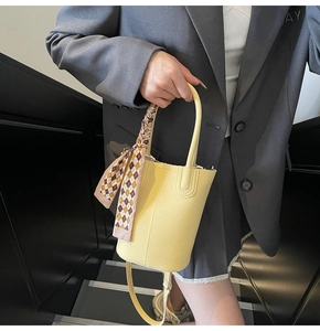 Detailed macro of yellow bucket bag with lychee texture and decorative silk scarf detail