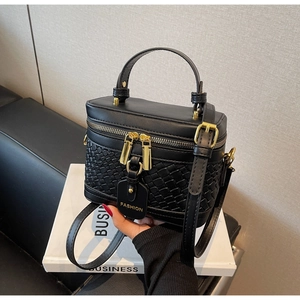 Detail of black PU leather handbag with woven pattern and gold zipper closures