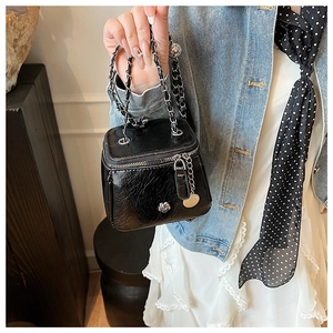 Détail du mini sac en cuir plissé noir brillant avec rose argentée et bandoulière