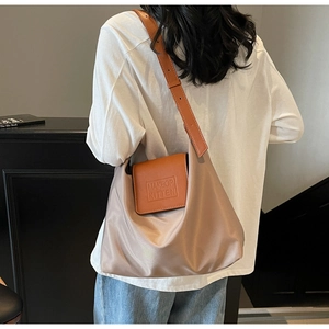 Détail du grand sac cabas plissé avec rabat en cuir marron et logo de la marque
