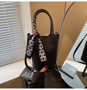 Detail of black lychee grain leather bucket bag with geometric silk scarf handle