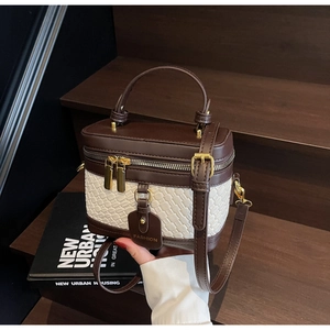 Detail of vanity case bag showing woven texture, golden zippers and leather luggage tag