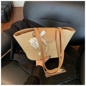 Detail of woven straw tote bag with brown leather flap and pearl lace bow decoration
