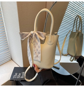 Detail of cream white bucket bag with pebble texture and decorative silk scarf