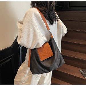 Vue détaillée du sac fourre-tout noir en nylon avec rabat orange porté par un mannequin