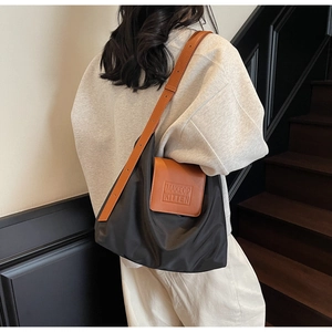 Détail du sac cabas en nylon noir plissé avec bandoulière en cuir porté par un mannequin