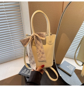 Close-up of cream bucket bag with lychee texture and decorative lattice silk scarf