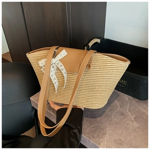 Detail of straw tote bag with brown leather flap and white lace bow with pearl pendant