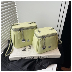 Détail du sac bandoulière vert clair plissé avec accents floraux en métal et bandoulière chaîne