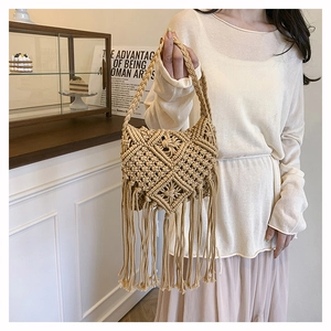 Detail shot of the beige cotton woven crossbody bag showing fringe and bohemian knot patterns
