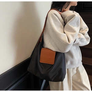 Détail du logo embossé sur le sac fourre-tout en nylon noir et cuir marron de qualité