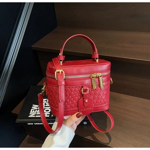 Detail view of red PU leather bucket bag with woven texture and gold dual zippers