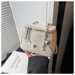 Détail du sac bandoulière en cuir plissé crème avec chaîne argentée et emblème camélia