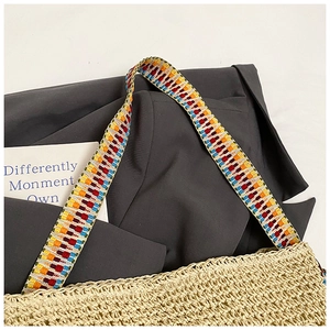 Gros plan d'un sac cabas en paille avec bandoulière brodée colorée au style bohème