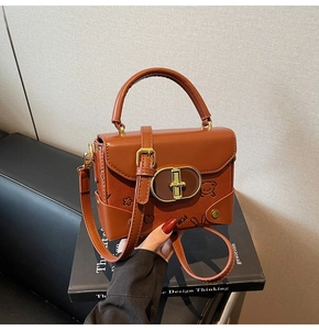 Detail of vintage brown leather handbag with cartoon embossing and gold metal clasp lock