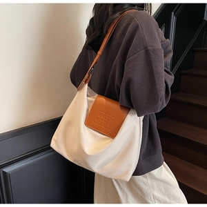 Détail du sac fourre-tout en tissu plissé avec bandoulière en cuir marron et logo