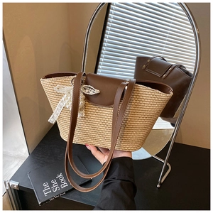 Detail of woven straw tote bag with brown leather trim and white lace pearl bow