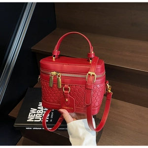 Detail of red PU leather bucket bag featuring woven texture and gold dual zipper design