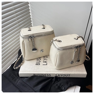 Détail du sac bandoulière crème avec ornements de rose et bandoulière en chaîne chic