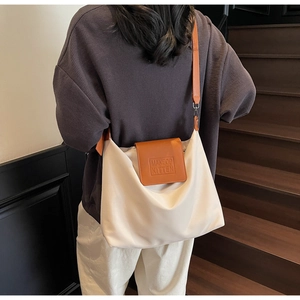 Détail du sac cabas en nylon blanc cassé avec rabat en cuir marron et logo embossé