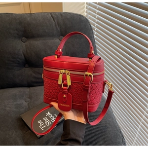 Detail of red PU leather bucket bag with woven texture and gold dual zipper closure