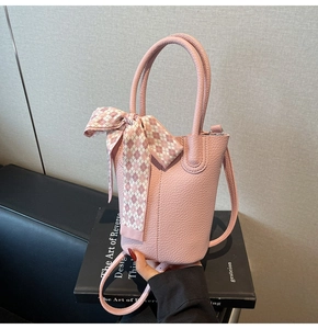 Pink lychee grain leather bucket bag with checkered scarf handle and slim strap detail