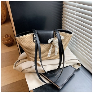 Detail of hand-woven straw tote with black leather flap and pearl lace bow charm