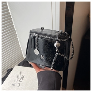 Vue détaillée d'un sac noir en cuir froissé avec bandoulière chaîne et camélia