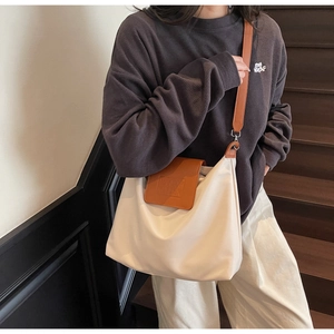 Détail du sac cabas minimaliste montrant le tissu beige et le rabat en cuir marron