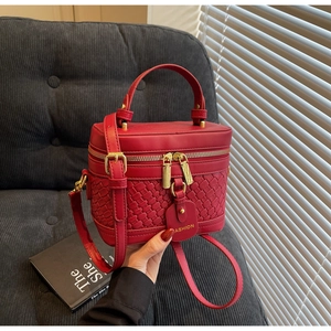 Detailed close-up of a red woven PU leather bucket bag with gold zippers and crossbody strap