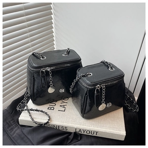Détail de sacs boîtes noirs en cuir verni brillant avec chaîne argentée et camélia